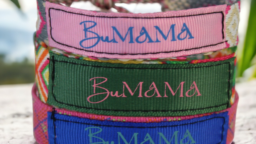 3 woven multi-colored music festival bracelets stack on top of each other with a palm leaf in the back.