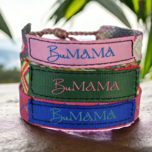 3 woven multi-colored music festival bracelets stack on top of each other with a palm leaf in the back.