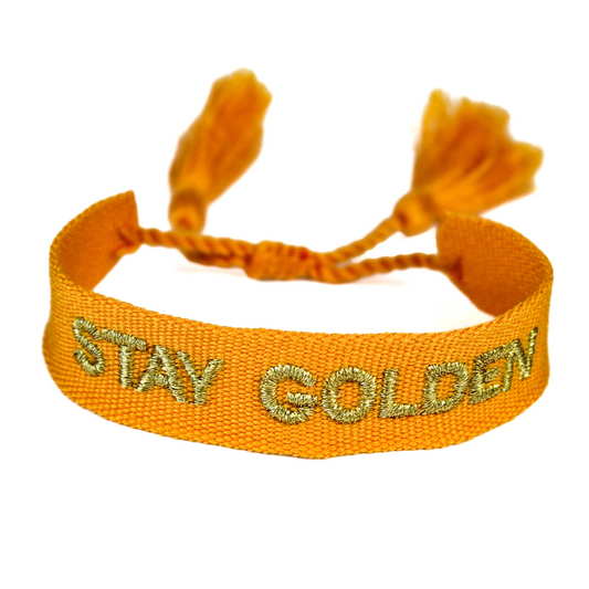 BuMama Stay Golden Woven Festival Bracelet in goldenrod with 'Stay Golden' embroidery and tie fastening.